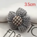 Handmade grey knitted woolen flower hair accessory with a brown checkered button center. - Gray