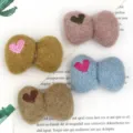 Close-up detail of cute felt bow hair clip accessories with embroidered heart patterns. - Heart / Blue