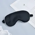 Black silk sleep mask with white piping and elastic strap for comfortable night travel rest. - Black with White Edge