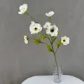 Nahaufnahme des künstlichen weißen Anemonen-Blumenzweigs in einer dekorativen Glasvase. - Weiß