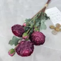 Primo piano di ranuncoli artificiali, fiori di seta viola scuro con foglie verdi. - Rosso