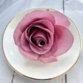 Detailed shot of dusty pink artificial rose flower head in white plate, floral accessory. - Light Purple