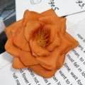 Primer plano detallado de rosa artificial de tela naranja, ideal para decoración. - Amarillo oscuro