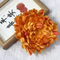 Artificial orange chrysanthemum flower head for hotel mall window decoration and floral arrangement. - Sunset