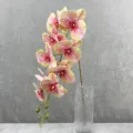 Gedetailleerde close-up van realistische kunstorchidee bloementak geplaatst in een heldere glazen vaas. - 7