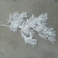 Detail view of white plastic artificial pine branch, perfect for wedding floral arrangement. - White