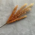 Detalle en primer plano de rama de caña de espiga de grano artificial para decoración floral. - Naranja