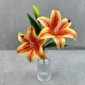 Gros plan de fleurs de lis artificielles avec deux têtes vibrantes et des bourgeons dans un vase. - N°3