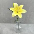 Detailed view of a single stem artificial yellow lily flower in a clear glass vase. - Yellow