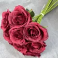 Close-up detail of artificial burgundy rose bouquet, artificial flower stem and green leaves. - Dark Red