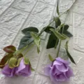 Primo piano di rose artificiali viola con foglie verdi per la decorazione della casa. - Viola chiaro