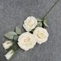 Artificial rose flower detail showing multiple blooms and green leaves for decoration. - Cream