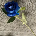 Gros plan détaillé d'une rose bleue artificielle avec des pétales vibrants, des feuilles et une tige. - Bleu saphir