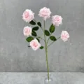 Gros plan d'une tige de rose artificielle rose avec des feuilles vertes dans un vase. - Rose Clair