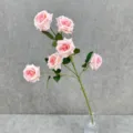 Gros plan d'une branche de roses artificielles roses avec feuilles vertes dans un vase. - Rose Clair