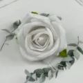 White velvet artificial rose flower head with eucalyptus leaves detail for wedding decor. - White