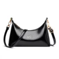 Black patent leather crescent shoulder bag with golden hardware and stylish underarm design. - Black