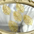 Gold hollow acrylic leaf decorations shown in close-up on a luxury vintage decorative mirror tray. - Gold Monstera Leaf