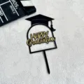Close up of black and gold acrylic graduation cake topper with cap design for party. - Happy Graduation