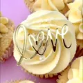 Close-up detail of a gold acrylic LOVE cake topper on a delicious frosted cupcake. - Love Shape / Width Approx. 6.5cm / Gold