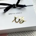 Close-up detail of gold mirror acrylic script ornament on white gift box with black ribbon. - Gold XB2 Cupcake Toppers