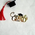 Gold acrylic Congrats Grad cake topper detail with black graduation cap and red tassel. - Graduation Style Four