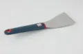 Stainless steel kitchen spatula with blue and red silicone handle detail view, durable tool. - Cake Server