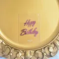 Close up detail view of transparent acrylic birthday cake topper with pink mirror finish text. - Mirror Rose Red + Transparent Tag Base