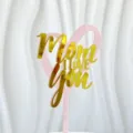 Primer plano detalle topper de tarta acrilico, corazon rosa con texto dorado Mom I love you. - Rosa y Oro Mamá Te Amo