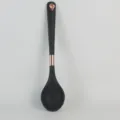 Vue détaillée d'une louche à soupe en silicone noir avec des accents or rose. - Cuillère de Service