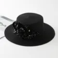 Detailansicht eines eleganten schwarzen Strohhutes mit floralen Verzierungen und Pailletten. - M (56-58cm) / Schwarz