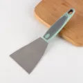 Stainless steel kitchen scraper with ergonomic green and grey handle for easy cooking use. - Turner