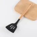 Paletta scanalata in silicone nero con manico in legno per variante di utensile da cucina. - Spatola forata