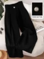Close-up detail view of high-waisted black wide-leg trousers featuring a fine decorative button. - S / Black