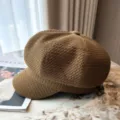 Detailopname van een bruine newsboy pet met honingraatmotief en getextureerde stofstructuur - koffiekleur