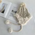 Gemütliche beige Strick-Trapper-Mütze mit Fellimitat, Ohrenklappen und süßen Pompoms für Winter. - Einheitsgröße / Aprikose