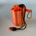Orange waterproof emergency poncho storage bag close up view with black drawstring. - Orange Raincoat Bag with Orange and Black Whistle and Carabiner