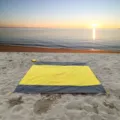 Detailaufnahme einer wasserdichten Stranddecke in Gelb und Grau am sandigen Meeresstrand. - 140*200cm / Gelb mit doppeltem Grau