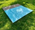 Outdoor picnic mat detail showing waterproof blue and grey fabric staked securely on green grass. - 200*210cm / Main Blue + Gray