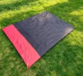 Outdoor camping waterproof picnic mat detail showing black and red folding design on grass. - Black and Red