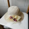 Cappello di paglia beige traforato con elegante fiore in nastro e dettaglio di perla. - Con Cordino Antivento / Beige