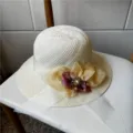 Vista dettagliata del cappello di paglia estivo con motivo traforato e fiore di perle. - Con Cordino Antivento / Bianco latte