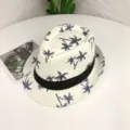 Gros plan détaillé du chapeau de paille blanc avec motif de palmiers bleus et ruban noir. - Taille adulte (56-58 cm) / Crème à Palmiers