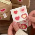 Valentine heart sticker detail showing multi-layer red pink and gold nested heart designs. - Korean Heart Gift Box Style