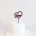 Detailed view of red and black acrylic heart love cake topper on white dummy base. - Mirror Red Love