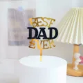 Father's Day acrylic cake topper detail view, showing the gold and black Best Dad Ever text design. - Good Dad