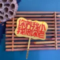 Close-up detail of the golden acrylic cake topper featuring engraved Chinese family blessing text. - Raised by You, Aging with You