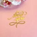 Gros plan détail de la décoration de gâteau love you en acrylique doré sur fond rose. - Love You Écriture Or