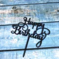 Detail shot of black acrylic Happy Birthday cake topper, elegant cursive party decor. - Black