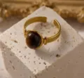Detailopname van gouden roestvrijstalen ring met bruine edelsteen op getextureerde steen. - Omtrek 54MM-US7 / Olijfgroen